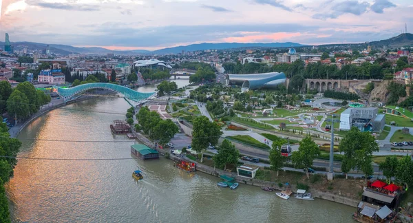 Tiflis, Georgien - Juni 2018: Rikiepark, Kura-Fluss und Friedensbrücke bei Sonnenuntergang, Luftaufnahme — Stockfoto
