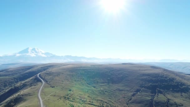 Mountain landscape, road in the mountains, in the distance Elbrus, beautiful glare from the sun, shooting from a height — Stock Video