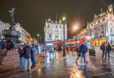 Londra - Ekim 2019: Anteros heykelinin yanındaki turistler yağmurdan sonra gece Piccadilly Sirki 'nde