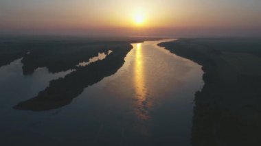 Güzel romantik manzara: nehrin üzerinde gün batımı, nehirde tekne, su parlıyor