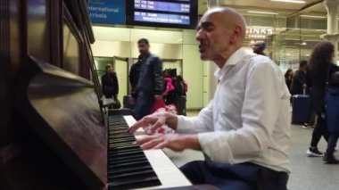 Londra - Ekim 2019: St. Pancras tren istasyonunda bir adam piyano çalar ve şarkı söyler.