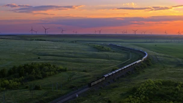 Train, chemin de fer dans la prairie, moulins à vent au loin, coucher de soleil, vue aérienne — Video