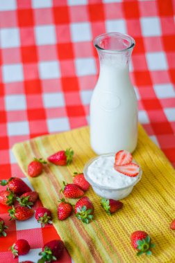 Lezzetli Sağlıklı Kahvaltı, cam şişe, çevresinde, çilek sarı Mutfak havlu üzerinde bir sürü küçük cam kase lezzetli yoğurt taze süt