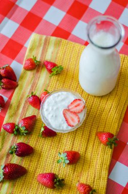 Lezzetli breakfast, cam şişe, çevresinde, çilek sarı mutfak havlusu, yan görünüm üzerinde bir sürü küçük cam kase lezzetli yoğurt taze süt