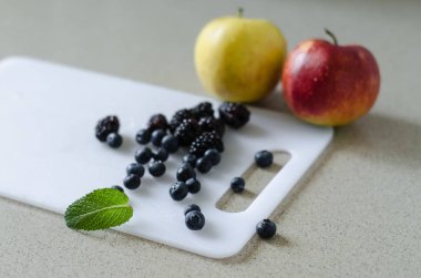 Taze elma, çilek ve nane yaprakları etrafında, Market beyaz kesme tahtası üzerinde taze yaz meyve