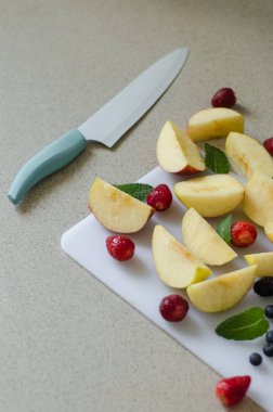 Taze elma dilimli, çilek nane yaprakları ve çevresinde, taze yaz meyve, beyaz kesme tahtası ve mutfak bıçak tarafında dikey fotoğraf