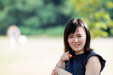 Parkta kameraya gösteren güzel bir Japon Bayan