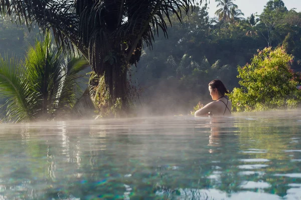 Een jonge vrouw ontspannen in een infinity pool — Stockfoto