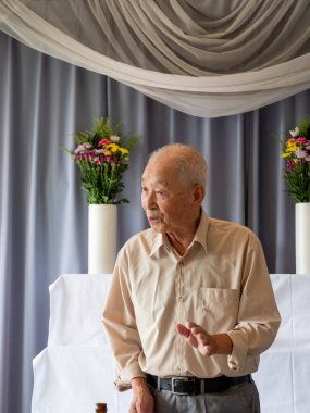 Yaşlı bir Asyalı aile etkinliğinde konuşma yapıyor.