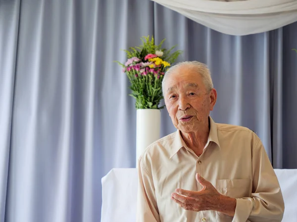 An elderly Asian man delivery a speech at a family event