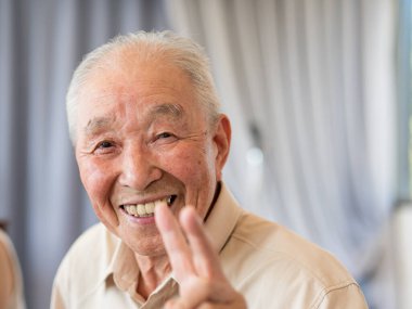 Gülümseyen ve barış işareti gösteren yaşlı bir adam.