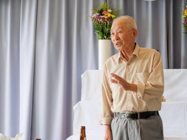 Yaşlı bir Asyalı aile etkinliğinde konuşma yapıyor.