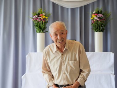 Yaşlı bir Asyalı aile etkinliğinde konuşma yapıyor.