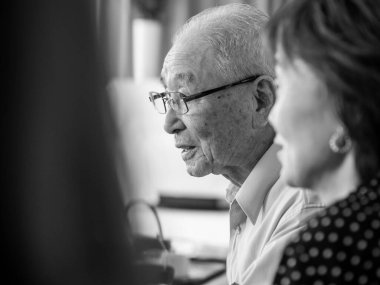 Ailesi etraftayken mutlu mesut konuşan çok yaşlı bir Asyalı.