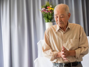 Yaşlı bir Asyalı aile etkinliğinde konuşma yapıyor.