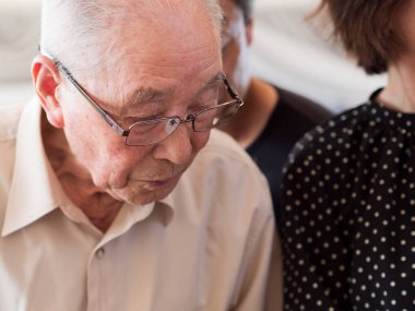 Yaşlı bir adam büyük bir ilgiyle aldığı bir şeye bakıyor.