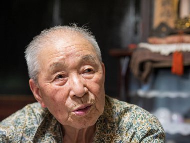 Yaşlı bir adam kamera önünde biriyle konuşuyor.