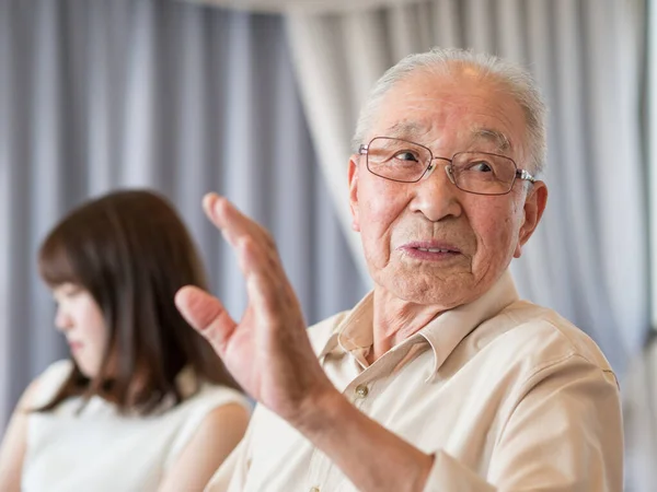 An old man talking animatedly at a family event