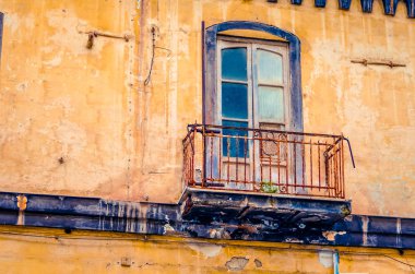 İtalya'da eski bir terk edilmiş ve çürüyen ev cephesinde vintage balkon