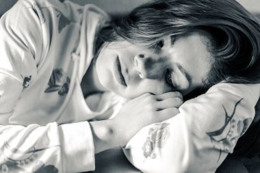 Esmer kız dinleniyor, başını kollarında tutuyor. siyah ve beyaz portre