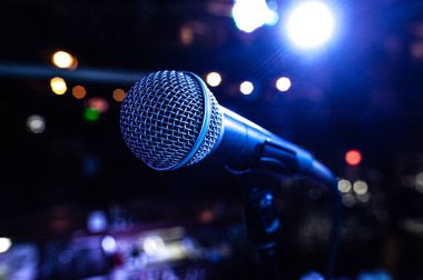 Sahnede bir konser sırasında arka planda renkli ışıklar olan mikrofon gövdesi.