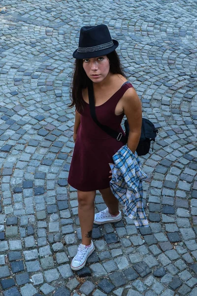 Молодая Брюнетка Бордовом Платье Черной Шляпе Стоит Тротуаре — стоковое фото