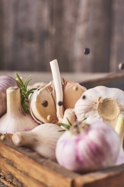 Yakın çekim görünümünü bir sürü taze Çiğ sarımsak ampuller ahşap kutu ve düşen siyah biber rustik gri arka plan üzerinde