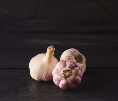 Siyah ahşap tahta üzerinde ham spacy sarımsak ampuller yakın çekim görünümü