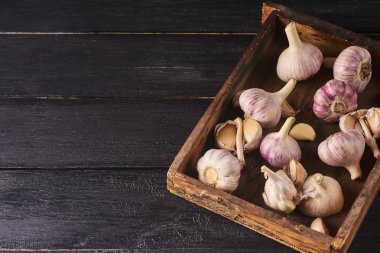 Taze Çiğ sarımsak ampuller ve ahşap kutusunda siyah ahşap zemin üzerine karanfil