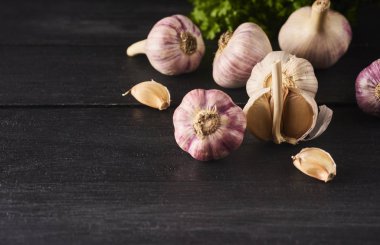 Çiğ spacy sarımsak ampuller ve fesh yeşil yakından görmek siyah ahşap kurulu yaprakları