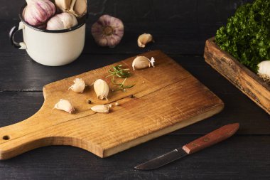 Taze Çiğ sarımsak karanfil bıçakla ccutting gemide. Siyah ahşap zemin üzerine beyaz kupa sarımsak ampuller