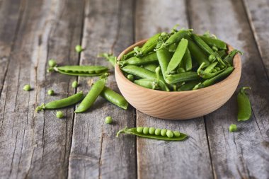 Hearthy taze yeşil bezelye ve bakla rustik ahşap zemin üzerine ahşap kase