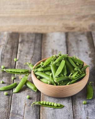 Hearthy taze yeşil bezelye ve bakla rustik ahşap zemin üzerine ahşap kase