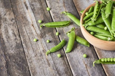 Hearthy taze yeşil bezelye ve bakla rustik ahşap zemin üzerine ahşap kase