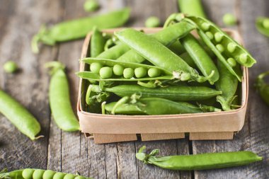 Hearthy taze yeşil bezelye ve bakla ahşap kutusunda yakın çekim görünümünü rustik arka plan üzerinde