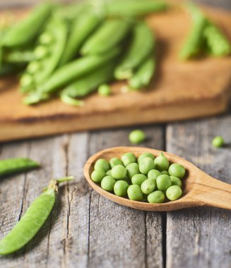 Hearthy taze yeşil bezelye ve bakla tahta kaşık içinde yakın çekim görünümünü rustik arka plan üzerinde