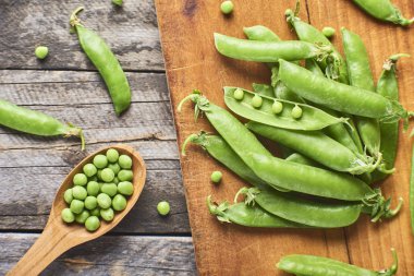 Hearthy taze yeşil bezelye ve bakla tahta kaşık içinde yakın çekim görünümünü rustik arka plan üzerinde