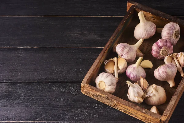 Taze Çiğ sarımsak ampuller ve ahşap kutusunda siyah ahşap zemin üzerine karanfil