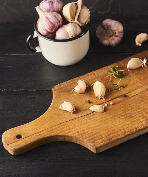 Taze Çiğ sarımsak karanfil bıçakla ccutting gemide. Siyah ahşap zemin üzerine beyaz kupa sarımsak ampuller