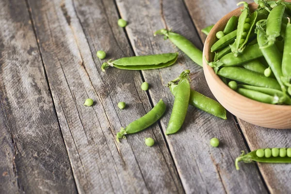 Hearthy taze yeşil bezelye ve bakla rustik ahşap zemin üzerine ahşap kase