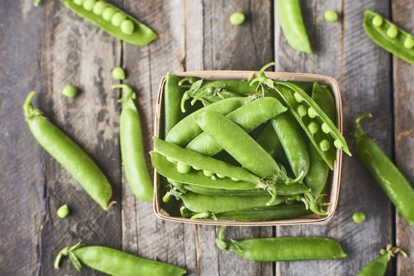 Hearthy taze yeşil bezelye ve bakla ahşap kutusunda yakın çekim görünümünü rustik arka plan üzerinde