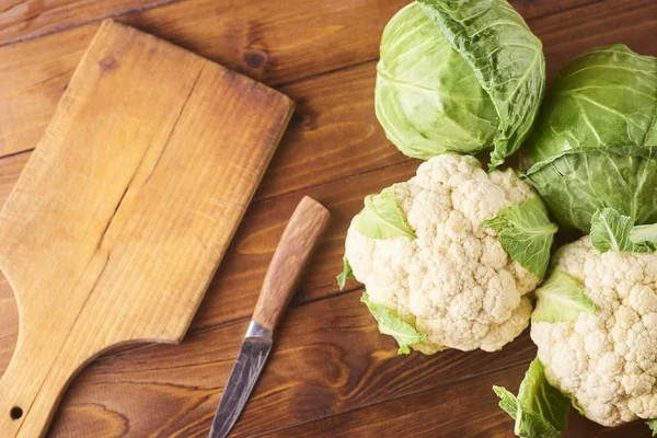 kesme tahtası ve ahşap arka plan üzerinde bıçak ile lahana türleri. Üstten görünüm