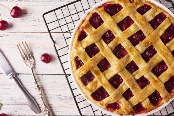 Delicious Homemade Cherry Pie with a Flaky Crust on rustic wooden white background. Top view