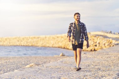 Açık hava yaşam tarzı görüntü ile neşeli gülümseyen adam sahilde yürüyor