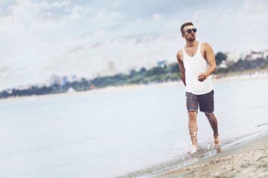 Açık hava yaşam tarzı görüntüdür genç yakışıklı adamla runing T-shirt ve şort giymiş sahilde