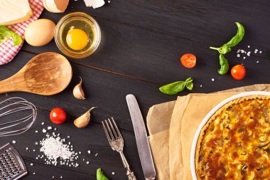 Tavuk, mantar ve peynir, mutfak eşyaları ve malzemeler ahşap arka plan siyah yemek pişirmek için ev yapımı quiche lorraine. Fransız mutfağı
