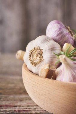 Taze Çiğ sarımsak ampuller küçük rosemary ile çok yakın çekim görünümünü ahşap kase rustik gri arka plan üzerinde bırakır.