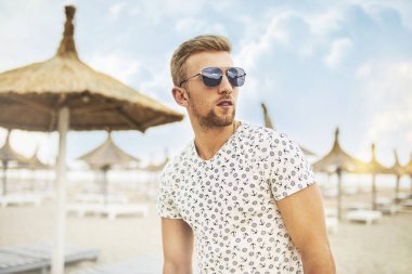 Açık dinlenme ve having fun güneşli kumsalda güneş gözlüğü yakışıklı bir adam portresi