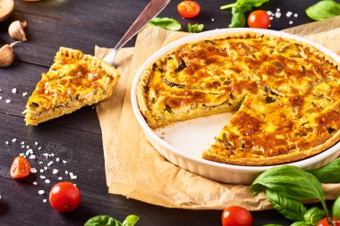 Bir parça ev yapımı quiche lorraine tavuk, mantar ve peynir, mutfak eşyaları ve siyah ahşap arka plan yemek pişirmek için malzemeler. Fransız mutfağı