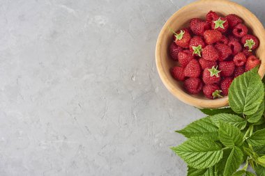 taze ve olgun ahududu ahşap kase, yeşil gri beton zemin üzerine bırakır. Üstten görünüm